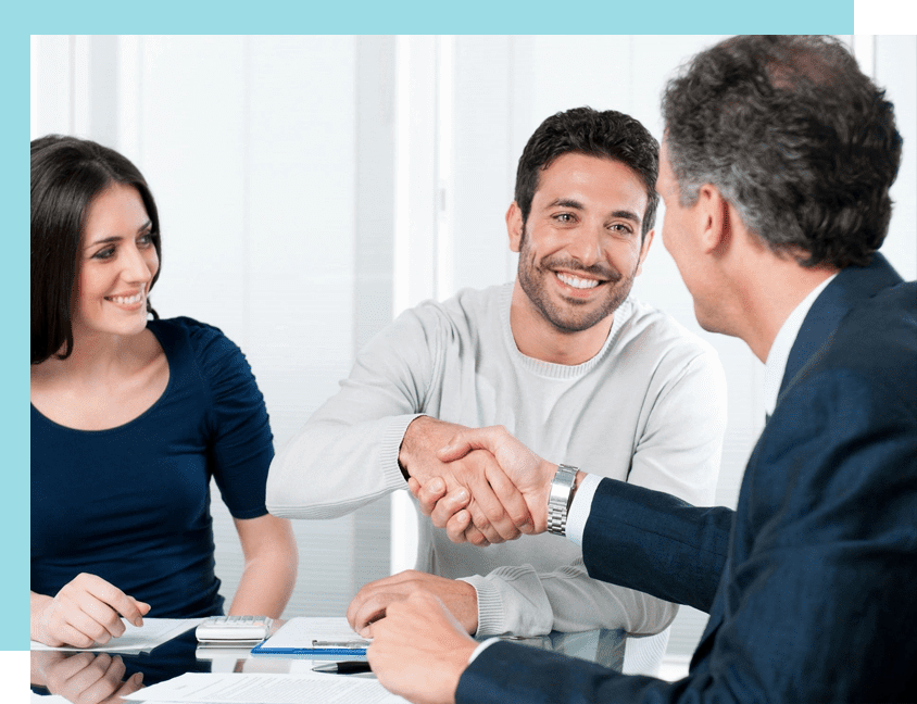 A man shaking hands with another man in front of two other people.